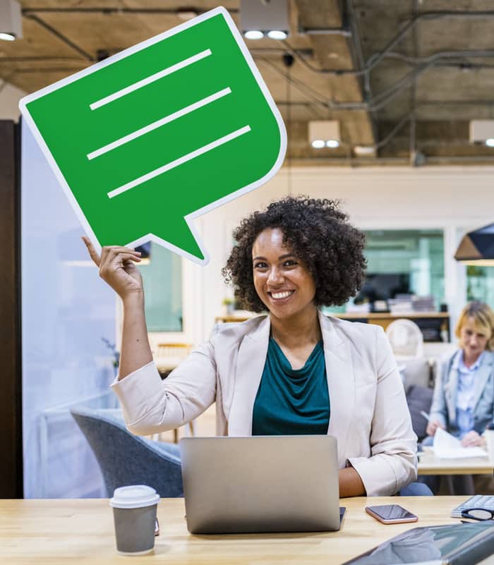 Mujer con computadora y letrero de diálogo verde